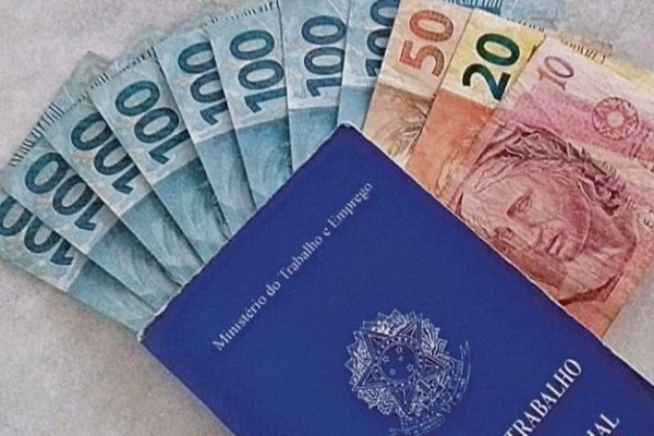 Carteira de trabalho ao lado de notas de real, representando as regras do 13º salário para trabalhadores com vínculo formal no Brasil.
